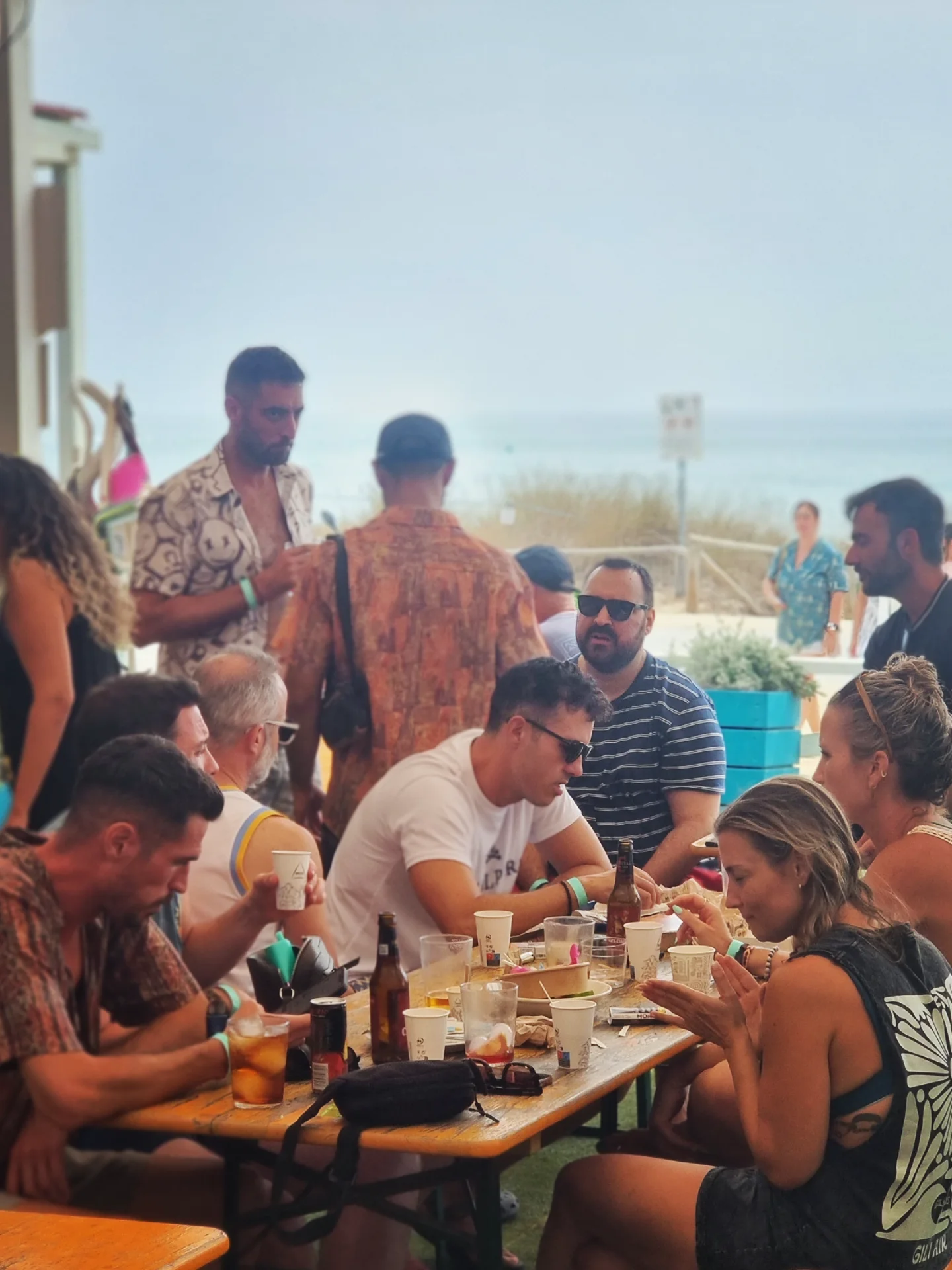 Mesa larga frente al mar con cervezas y amigos